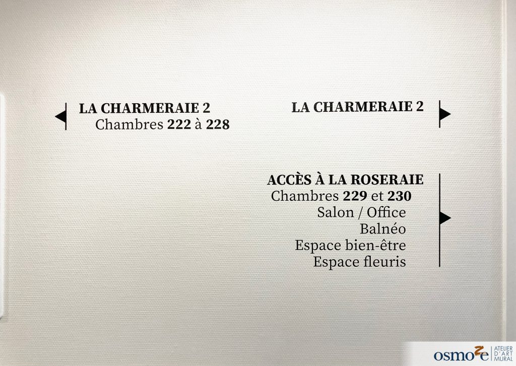 Signalétique directionnelle noir sur mur blanc dans un EHPAD